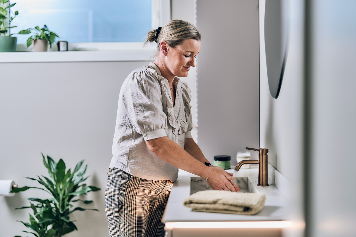 Kvinne vasker hendende i vasken på badet.