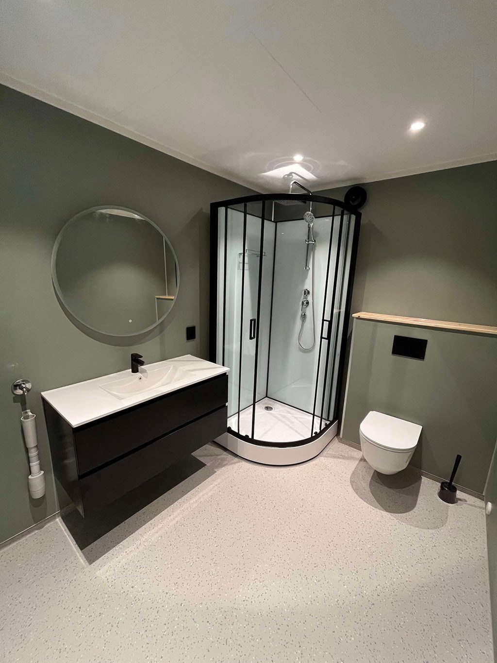 Baderomsmøbel i sort med hvit nedfelt servant. Dusjkabinett med sorte sprosser og vegghengt toalett.?